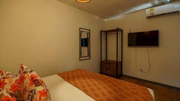 Un dormitorio con cama, espejo, armario y televisor en la pared.