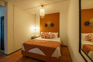 Un dormitorio con cama, mesita de noche, lámpara de pared y adornos de platos.