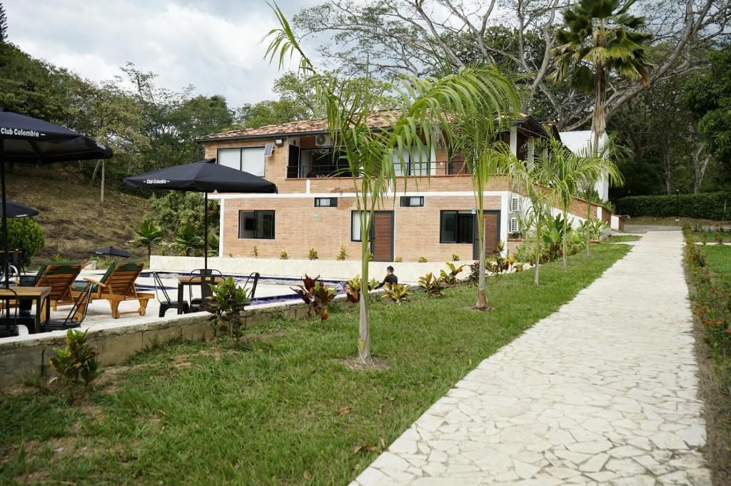 Una casa de dos pisos con un patio, mobiliario exterior y un camino que lleva a la entrada.