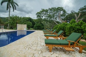 A poolside area with a clear blue pool, wooden lounge chairs, and a stone-tiled deck. - Tres Lagos Hotel (San Jerónimo)