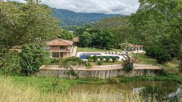 Una villa con piscina, immersa nel verde rigoglioso e con montagne sullo sfondo.