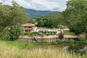 A villa with a swimming pool, surrounded by lush greenery and mountains in the background. - Tres Lagos Hotel (San Jerónimo)