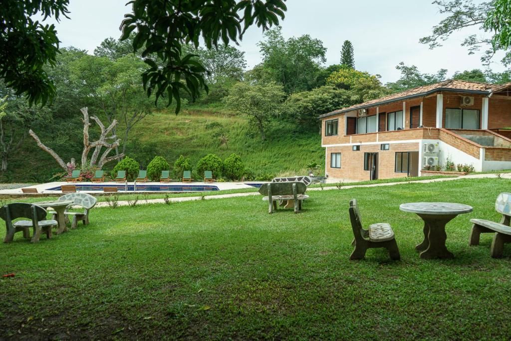 Una casa a due piani con piscina, immersa in un prato curato e circondata da mobili da giardino.