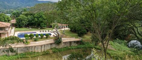 Un resort con piscina, un puente y vistas de la vegetación y montañas circundantes.