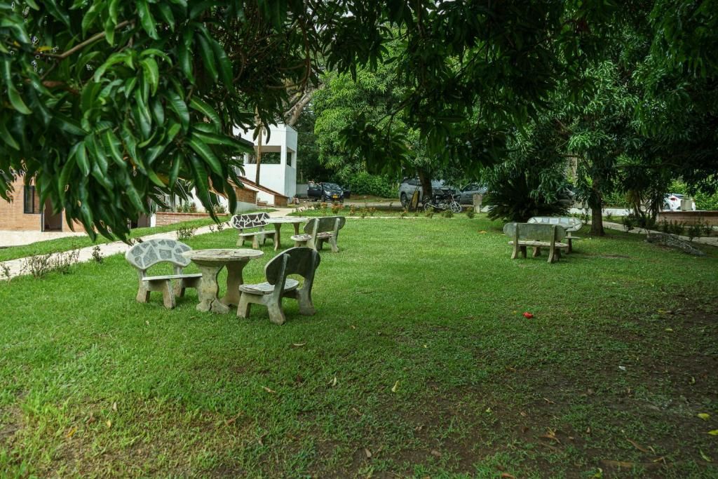 Zona esterna con tavoli e sedie in pietra, immersa nel verde e alberi.