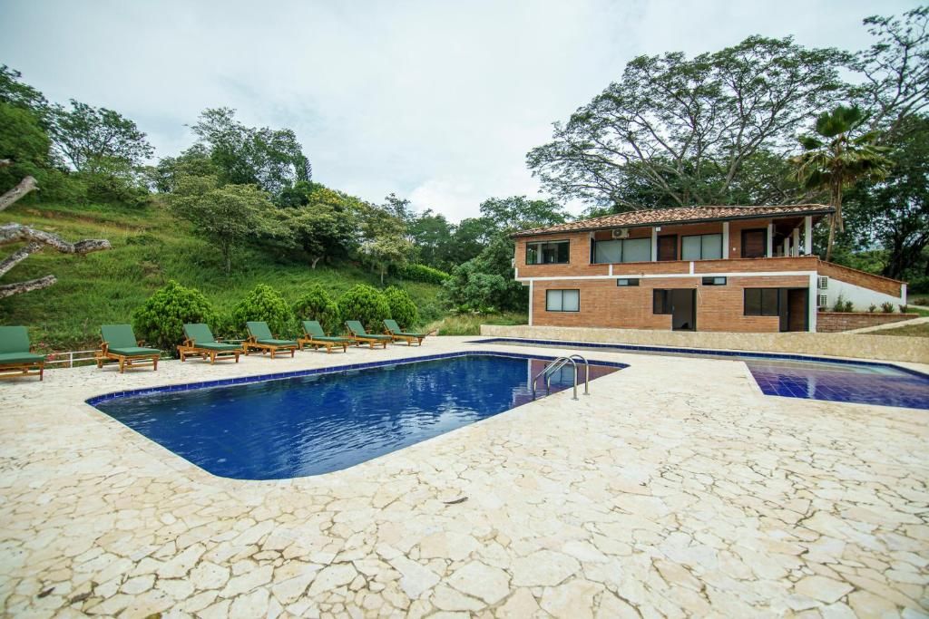 Un edificio de dos pisos con piscina y sillas de descanso.