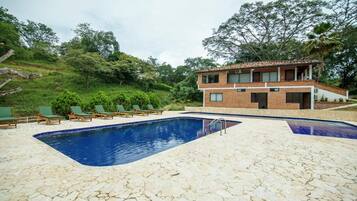 Un edificio de dos pisos con piscina y sillas de descanso.