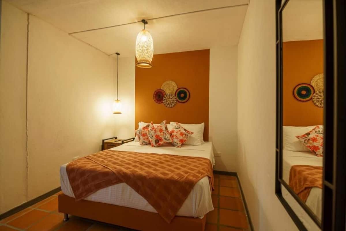 A hotel room with a bed, a nightstand, a lamp, and decorative wall art.