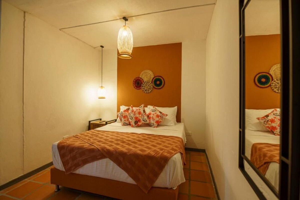 Une chambre d’hôtel comprenant un lit, une table de chevet, une lampe et des œuvres d’art décoratives accrochées au mur.
