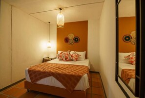 A hotel room with a bed, a nightstand, a lamp, and decorative wall art. - Tres Lagos Hotel (San Jerónimo)
