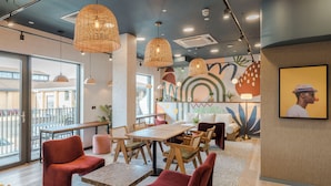 A modern cafe with wooden furniture, red chairs, and large windows offering a view of the street. - Milton Keynes - Your Apartment (Milton Keynes)