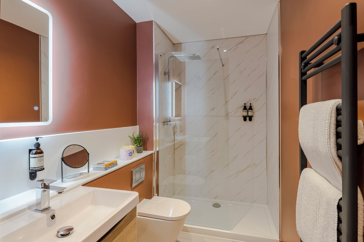 Une salle de bain moderne avec une douche à parois de verre, un lavabo blanc et un porte-serviettes.