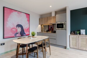 Una cocina moderna con comedor, que presenta un cuadro grande, armarios de madera y un microondas integrado.