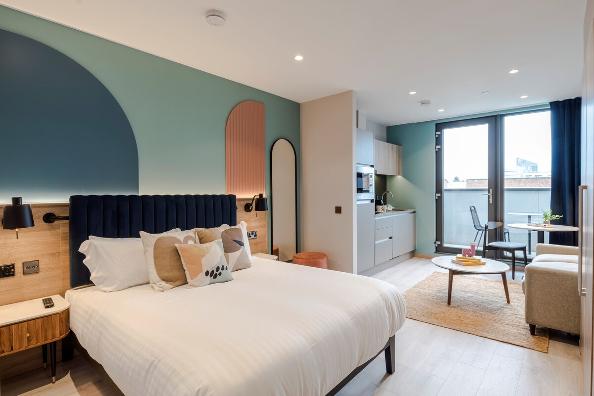 Una habitación de hotel moderna con una cama grande, un escritorio y un rincón de comedor.