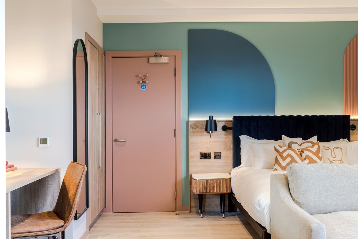 Une chambre à coucher comprenant un lit, une table de chevet, une chaise et une porte avec une pancarte.
