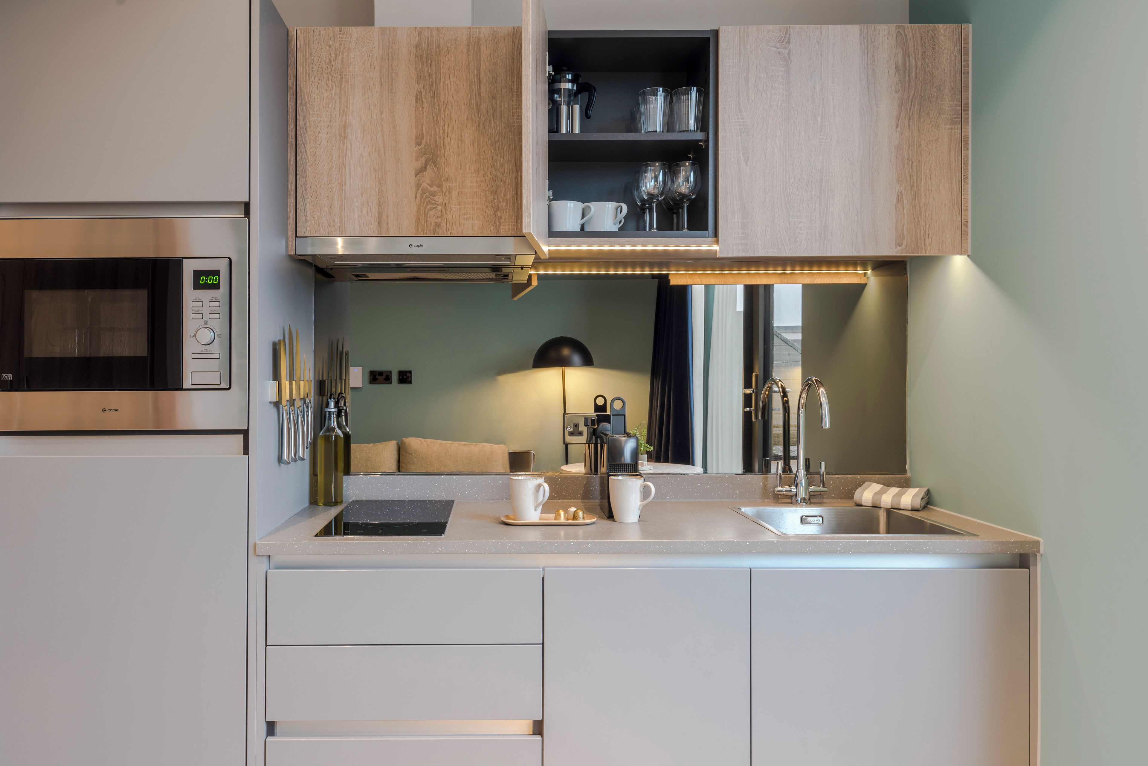 Una cocina moderna con microondas integrado, un fregadero y armarios de madera.