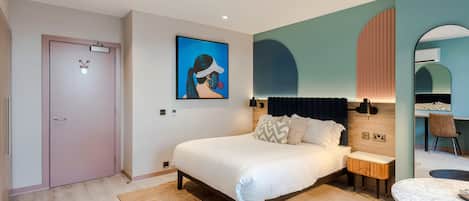 Un dormitorio moderno con una cama grande, mesitas de noche, una zona de estar pequeña y una mesa de comedor.