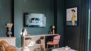 A modern living room with a sofa, a chair, a coffee table, a bookshelf, and a TV mounted on the wall.