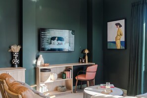 Una sala de estar moderna con un sofá, un sillón, una mesa de centro, una estantería y un televisor montado en la pared.