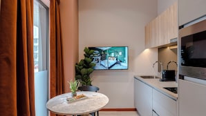 A modern kitchen with a marble countertop, a dining area with a round table, and a large flat-screen TV mounted on the wall. - Milton Keynes - Your Apartment (Milton Keynes)