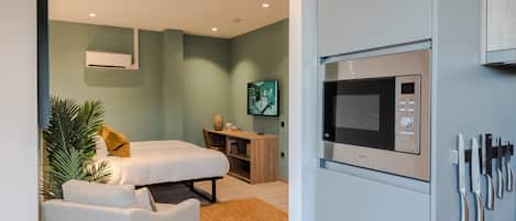 Un dormitorio moderno con una cama, un escritorio y un microondas integrado.