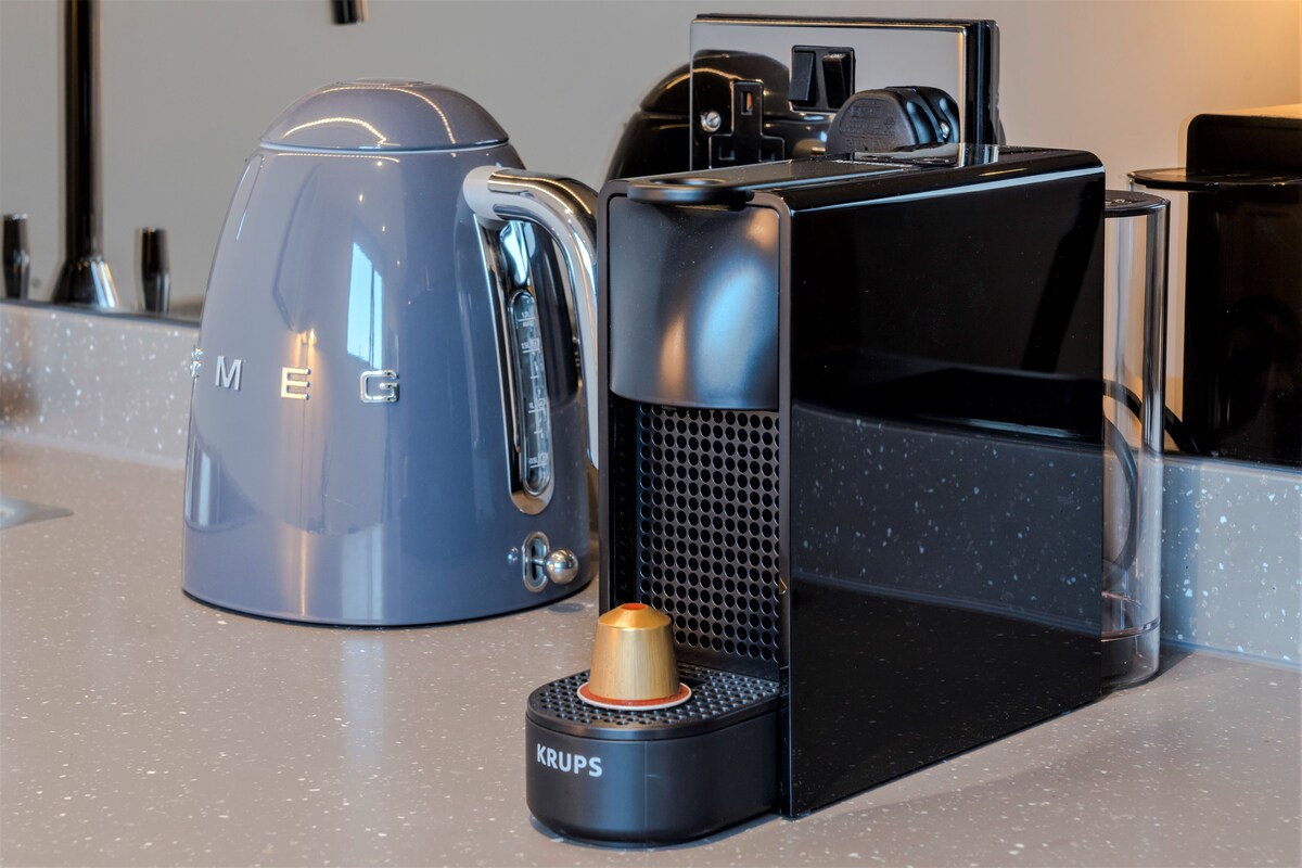 A coffee machine, a kettle, and a Krups coffee grinder on a countertop.