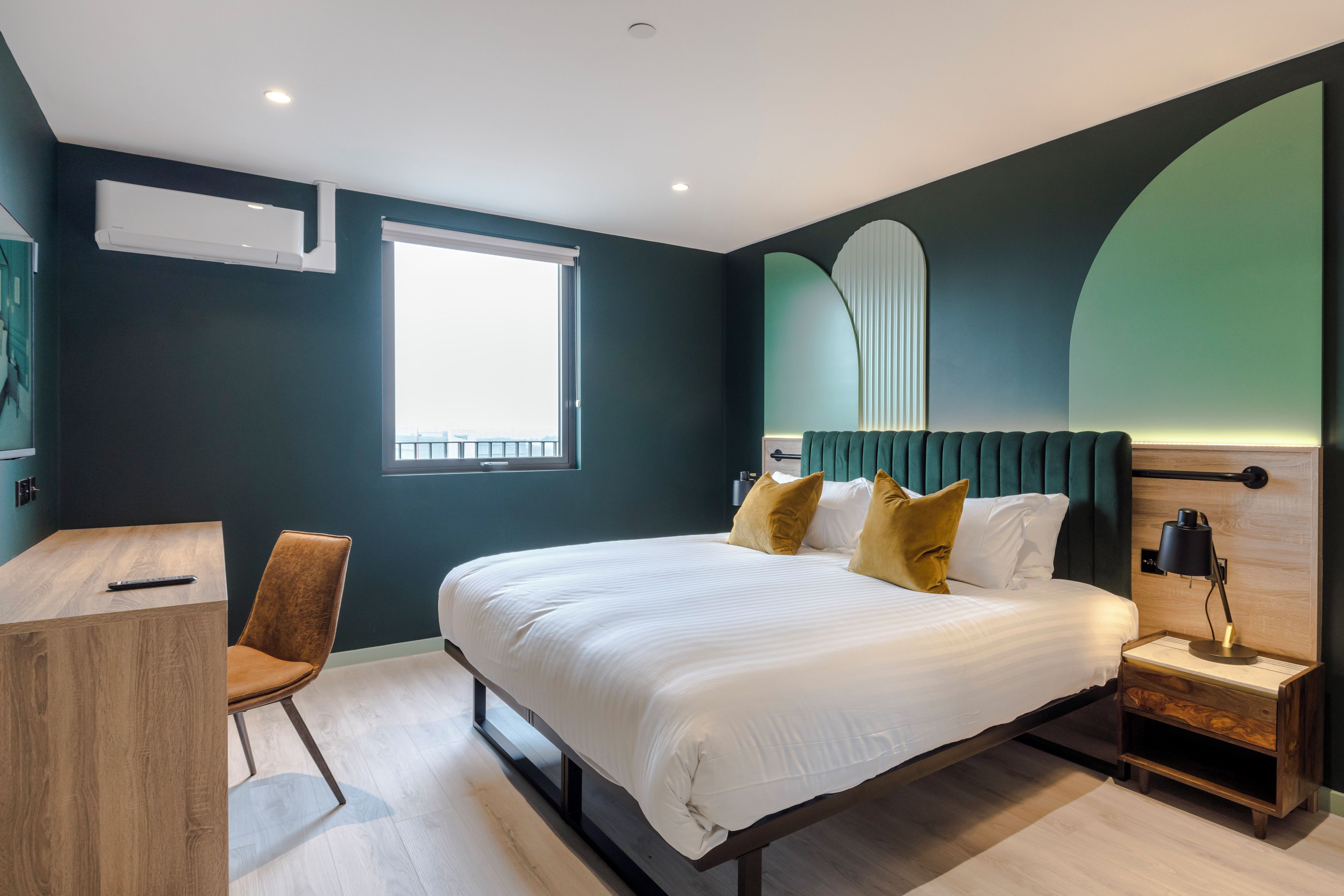 A modern bedroom with a large bed, a desk, and a chair.