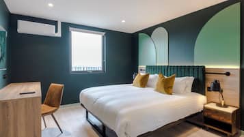 A modern bedroom with a large bed, a desk, and a chair.