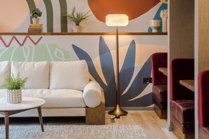 A modern living room with a sofa, a round coffee table, a floor lamp, and a vibrant abstract wall mural. - Milton Keynes - Your Apartment (Milton Keynes)