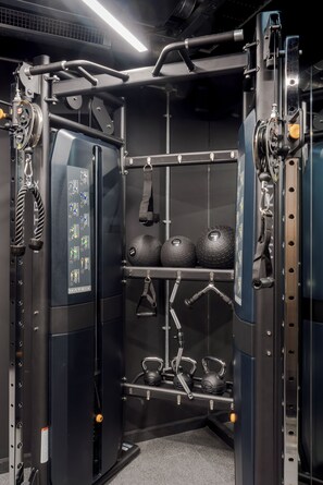 Une salle de sport équipée d’un support à squats, de kettlebells et de bandes de résistance.