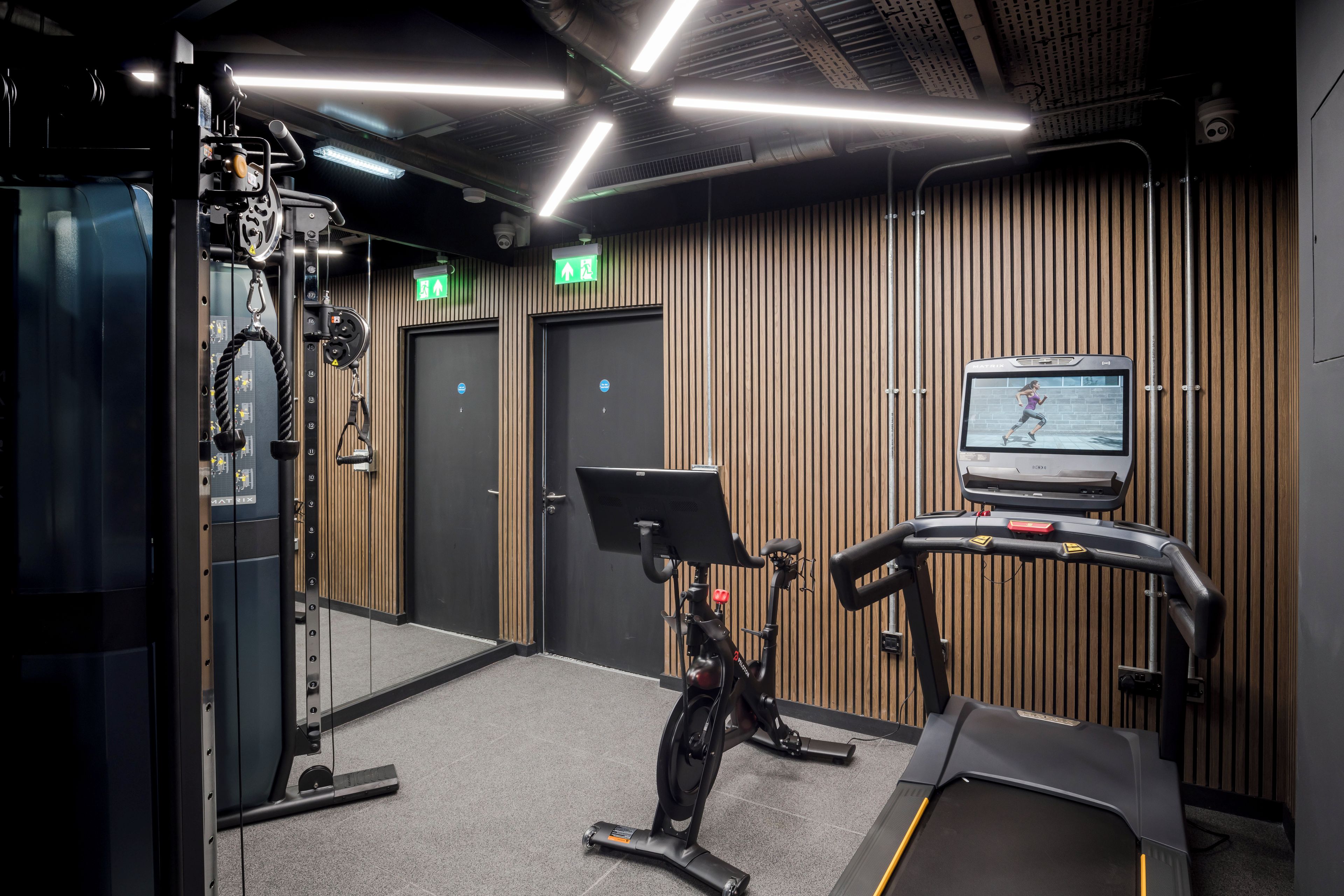 Una palestra con attrezzature per esercizi, tapis roulant e uno schermo TV a parete.