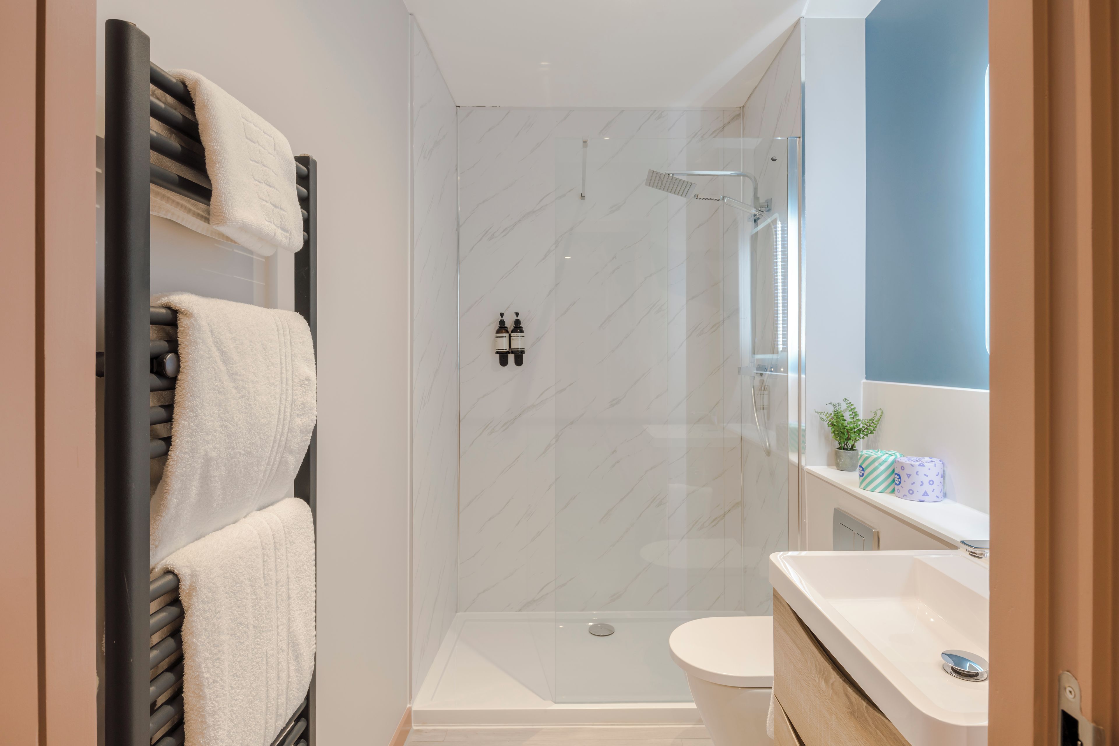 Un baño moderno con ducha envuelta en vidrio, inodoro blanco y tocador con espejo.
