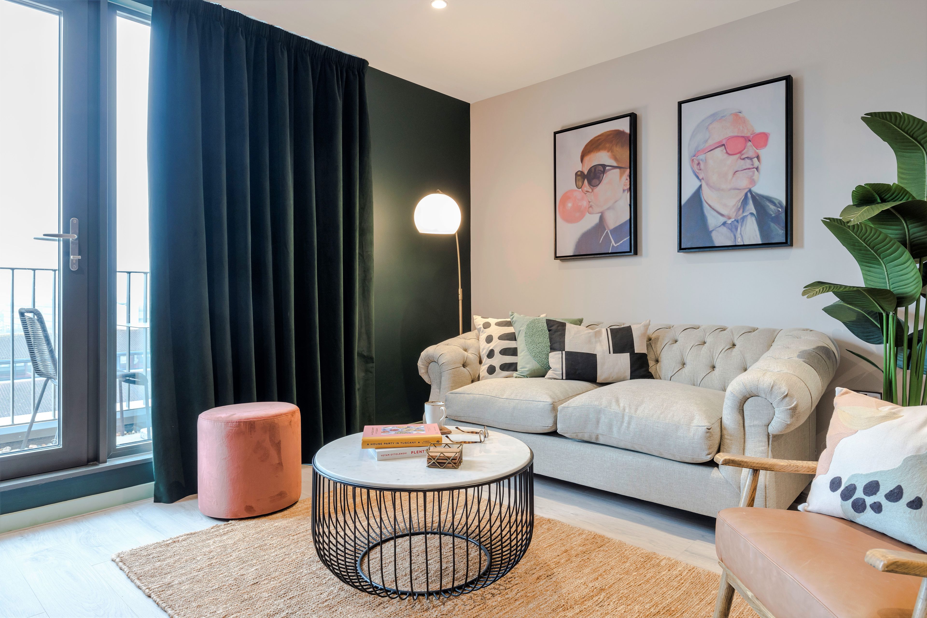 A modern living room with a sofa, round coffee table, and a large window with curtains.