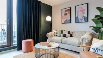 A modern living room with a sofa, round coffee table, and a large window with curtains.
