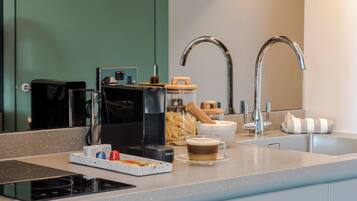 A modern kitchen with a built-in coffee machine, a kettle, and a coffee cup on the counter.