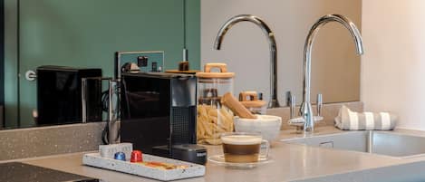 A modern kitchen with a built-in coffee machine, a kettle, and a coffee cup on the counter.