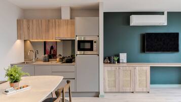 Cocina moderna con microondas, estufa y pileta integrados. Hay un comedor con mesa y sillas, y un televisor montado en la pared.