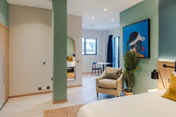 Une chambre d’hôtel moderne équipée d’un lit, d’un canapé, d’un bureau et d’une grande fenêtre.