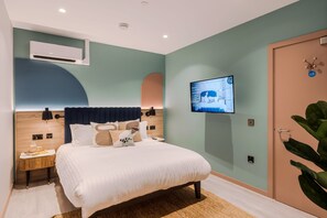 Un dormitorio moderno con cama, mesita de noche y televisor montado en la pared.