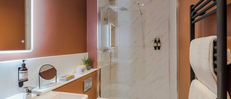A modern bathroom with a glass-enclosed shower, a white sink, and a towel rack.