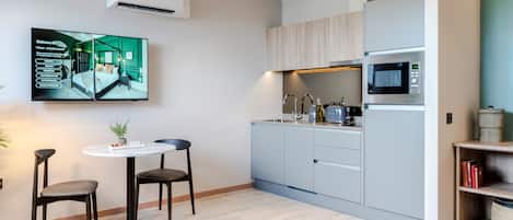 Un apartamento moderno con cocina, comedor y televisor de pantalla plana en la pared.