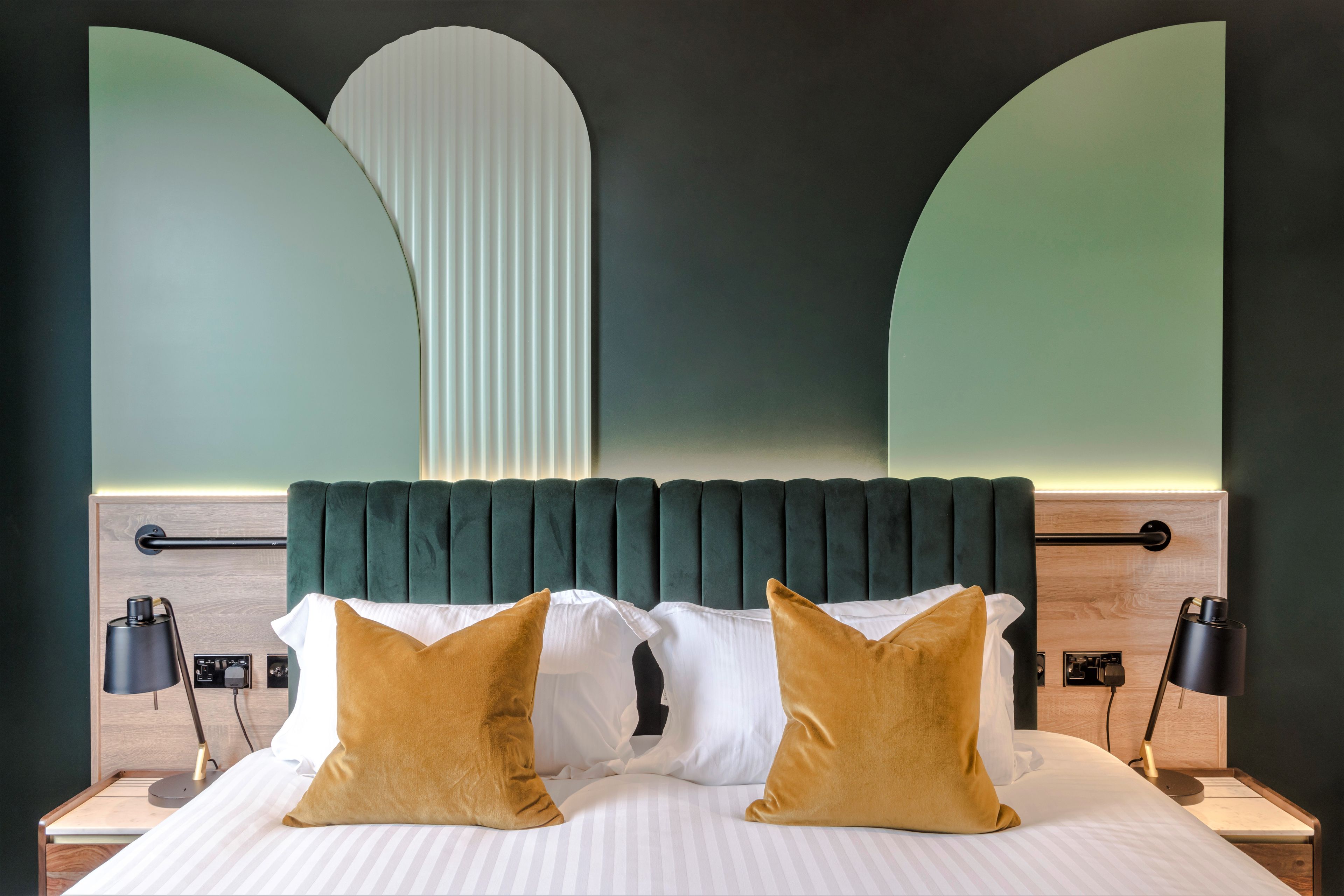 A neatly made bed with two pillows, a headboard, bedside tables, and lamps.