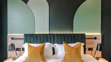 A neatly made bed with two pillows, a headboard, bedside tables, and lamps.