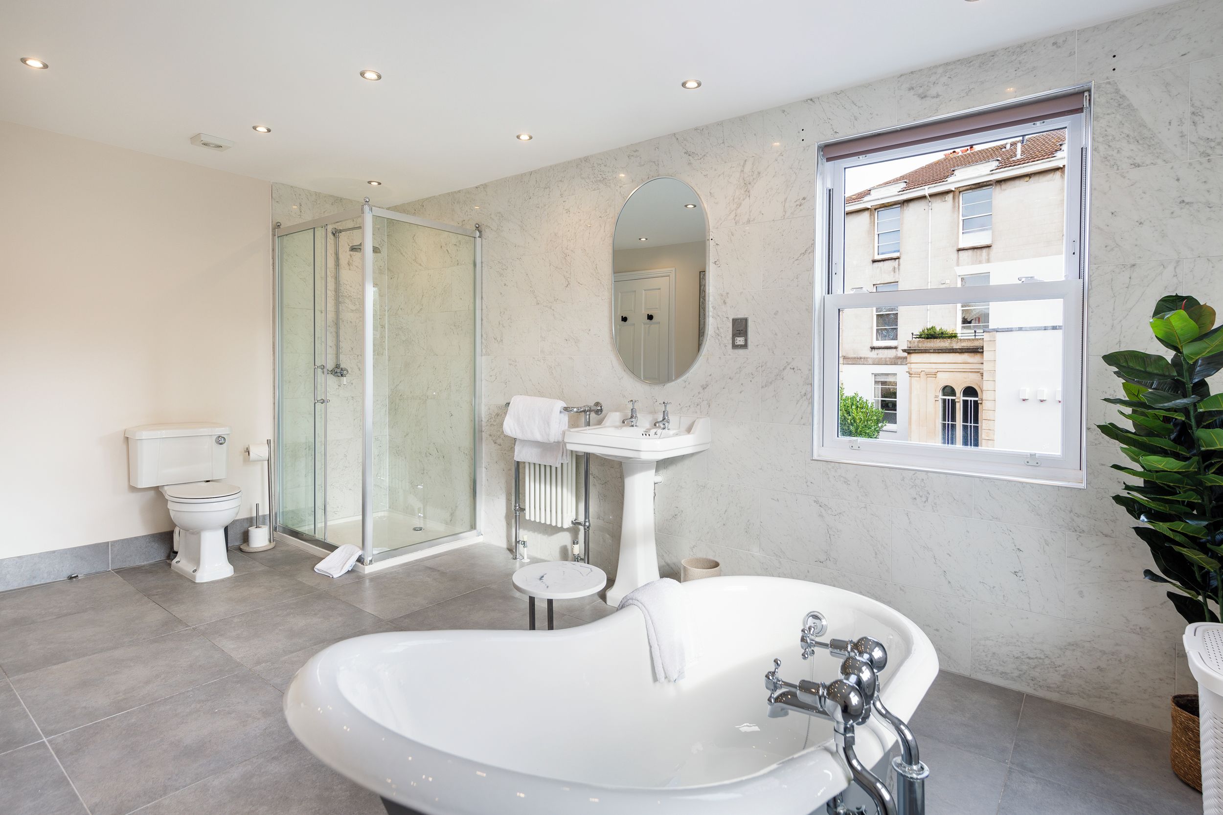 Un baño moderno con una bañera independiente, cabina de ducha con mampara de vidrio, inodoro y lavamanos.