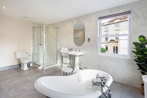 Une salle de bain moderne avec une baignoire sur pieds, une douche à parois de verre, des toilettes et un lavabo.