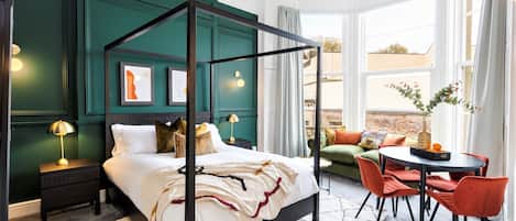 Un dormitorio moderno con cama con dosel, una pared de acento verde y vistas al exterior a través de amplios ventanales.