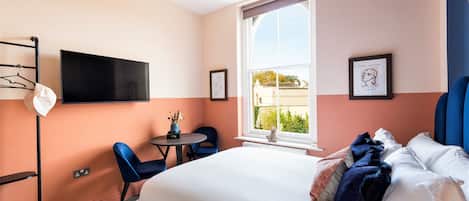 Un dormitorio con cama, escritorio, silla, televisor y ventana con vistas.