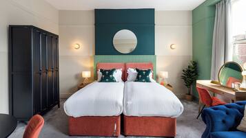 A double bed with two nightstands, a desk with a chair, a wardrobe, and a mirror.
