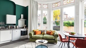 Une cuisine moderne avec des meubles blancs, un canapé vert et une table à manger avec des chaises rouges.