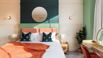 A bedroom with a bed, bedside table, chair, and a desk with a mirror.